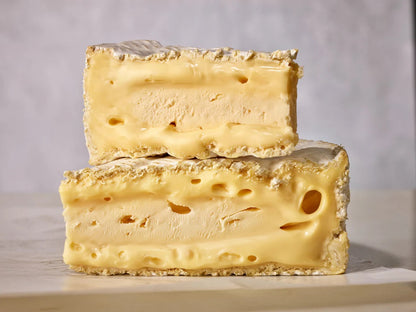 Two blocks of cheese stacked on a neutral background