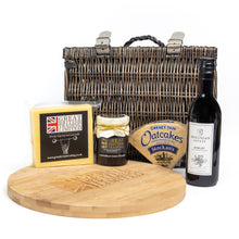 Gourmet gift set with a basket, cheese, jam, oatcakes, and wine on a white background