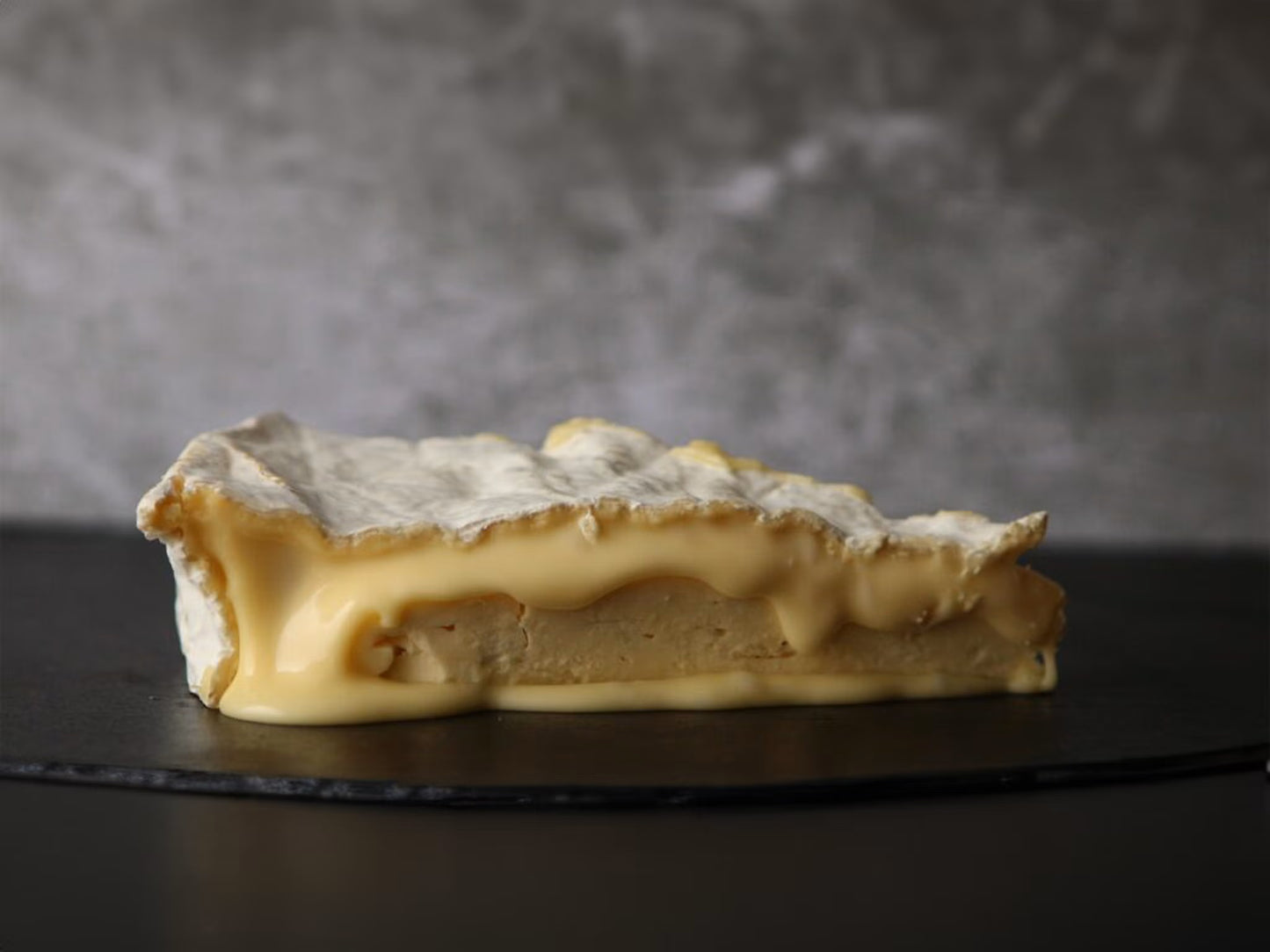 Slice of caramelized dessert on a dark surface with a gray background