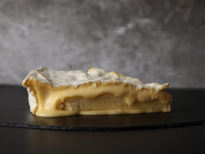 Slice of caramelized dessert on a dark surface with a gray background